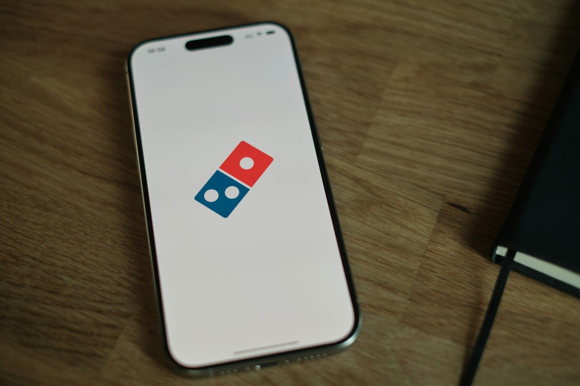 A white cell phone with a blue and red domino logo on it