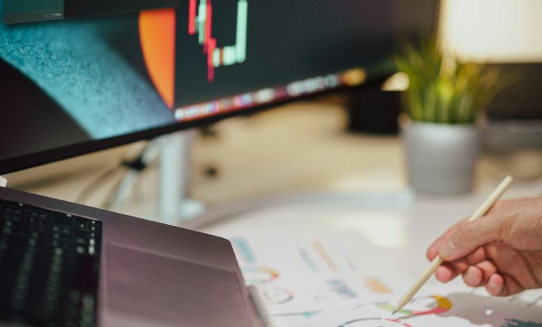 a person writing on a piece of paper next to a computer monitor