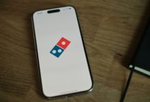 A white cell phone with a blue and red domino logo on it