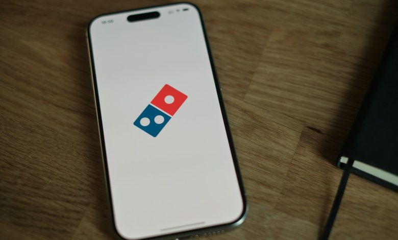 A white cell phone with a blue and red domino logo on it