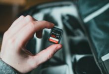 person holding black and red nintendo game cartridge