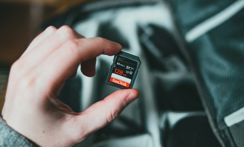 person holding black and red nintendo game cartridge