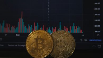 Gold Bitcoin and silver Ethereum coins resting on a laptop keyboard before a trading chart