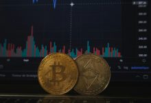 Gold Bitcoin and silver Ethereum coins resting on a laptop keyboard before a trading chart