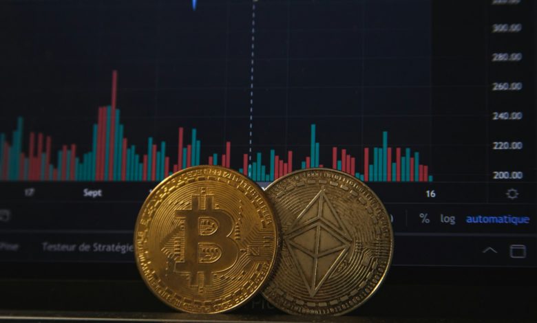 Gold Bitcoin and silver Ethereum coins resting on a laptop keyboard before a trading chart